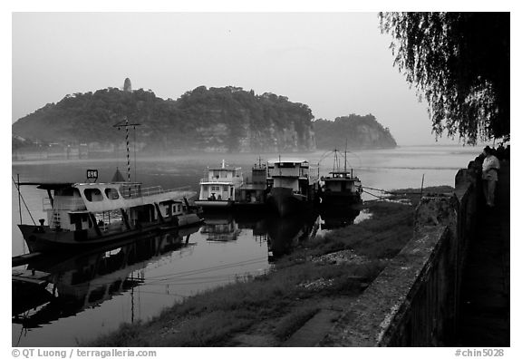 Boats along the river with cliffs in the background. Leshan, Sichuan, China (black and white)