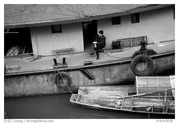 Man sitting on a house boat. Leshan, Sichuan, China (black and white)