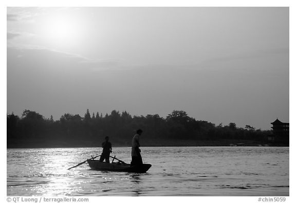 Fishermen at the confluence of the Dadu He and Min He rivers at sunset. Leshan, Sichuan, China (black and white)