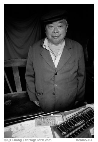 Man in a ticket booth with a counting frame. Leshan, Sichuan, China (black and white)