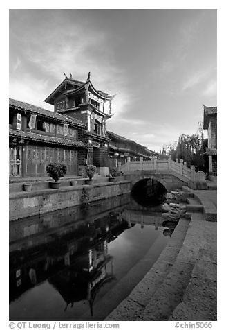 Kegong tower (memorial archway of imperial exam) reflected in canal, sunrise. Lijiang, Yunnan, China (black and white)