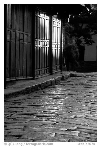 Cobblestone street and wooden doors at sunrise. Lijiang, Yunnan, China (black and white)