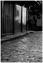 Cobblestone street and wooden doors at sunrise. Lijiang, Yunnan, China (black and white)