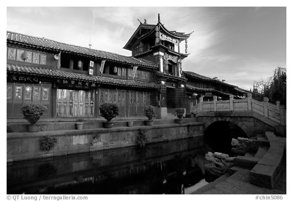 Kegong tower (memorial archway of imperial exam) reflected in canal, sunrise. Lijiang, Yunnan, China (black and white)