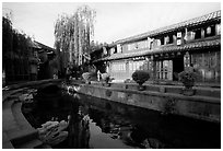 Buildings on Square street reflected in canal, sunrise. Lijiang, Yunnan, China (black and white)