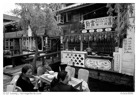 Women eat outside the Snack Food in Lijiang restaurant. Lijiang, Yunnan, China (black and white)