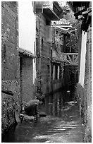 Woman washes clothes in the canal. Lijiang, Yunnan, China ( black and white)