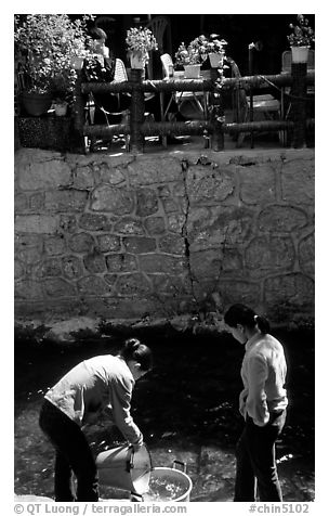 Women washing clothes in a canal. Lijiang, Yunnan, China