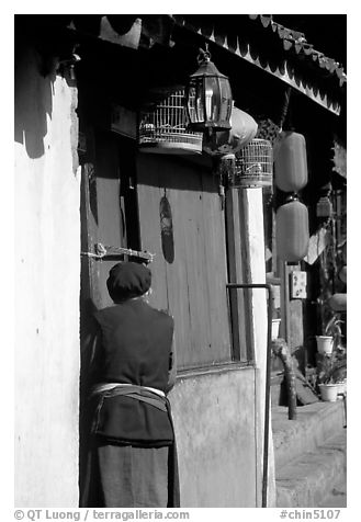 Naxi woman at the door of her wooden house. Lijiang, Yunnan, China (black and white)