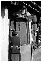 Naxi woman at the door of her wooden house. Lijiang, Yunnan, China (black and white)