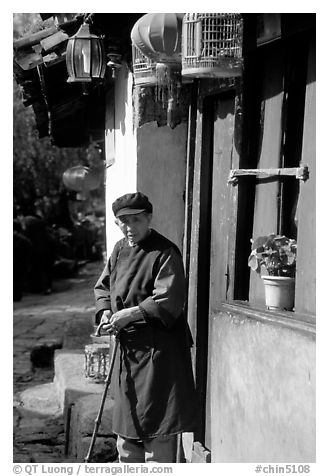 Naxi woman at the door of her wooden house. Lijiang, Yunnan, China (black and white)