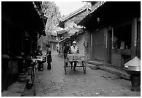 Early morning activity in a cobblestone street. Lijiang, Yunnan, China (black and white)