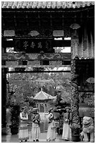 Women in Naxi dress standing in an archway. Lijiang, Yunnan, China (black and white)