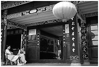 Women sit ouside  the Wufeng Lou (Five Phoenix Hall). Lijiang, Yunnan, China ( black and white)