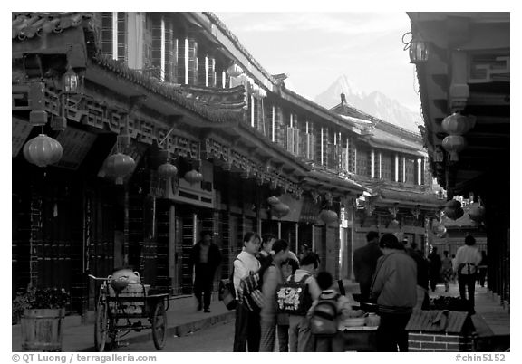 Schoolchildren get Naxi flatbread for breakfast, Jade Dragon Snow Mountain in the background. Lijiang, Yunnan, China (black and white)