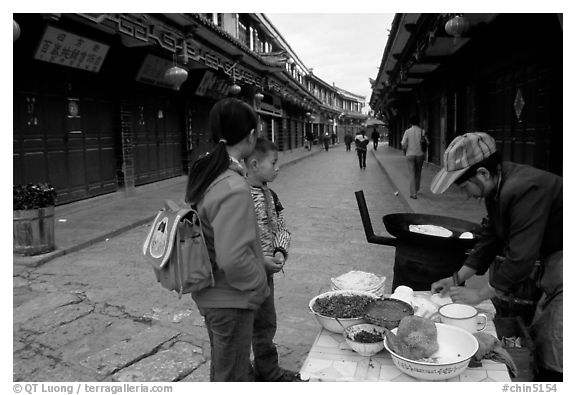 Schoolchildren get Naxi flatbread for breakfast. Lijiang, Yunnan, China (black and white)