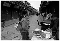 Schoolchildren get Naxi flatbread for breakfast. Lijiang, Yunnan, China (black and white)