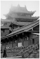 Monk beneath Jinding Si (Golden Summit) temple in the fog. Emei Shan, Sichuan, China ( black and white)