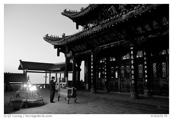 Pilgrim prays in the Jinding Si (Golden Summit) temple at dusk. Emei Shan, Sichuan, China (black and white)