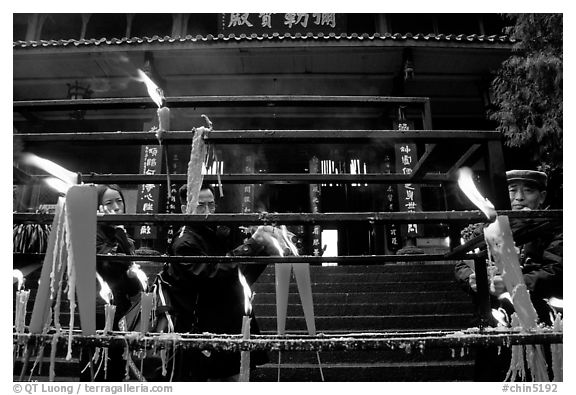 Pilgrims lighting incense sticks with Wannian Si temple in the background. Emei Shan, Sichuan, China (black and white)