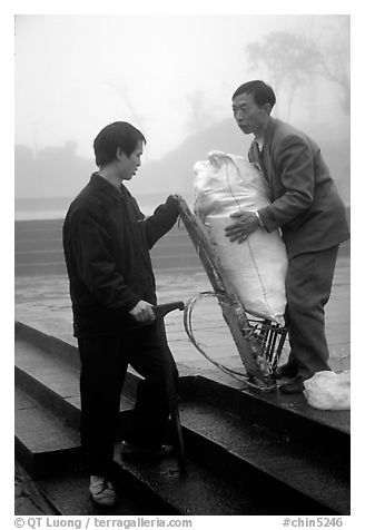 Porter getting ready to carry a heavy load on a back frame. Emei Shan, Sichuan, China (black and white)