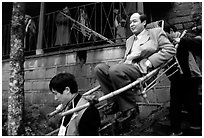 Wealthy pilgrim carried down Jieyin Palace on a chair. Emei Shan, Sichuan, China (black and white)