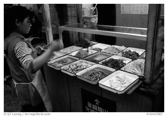 Woman helping herself to food. Sichuan food is among China's spiciest. Chengdu, Sichuan, China (black and white)