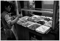 Woman helping herself to food. Sichuan food is among China's spiciest. Chengdu, Sichuan, China (black and white)