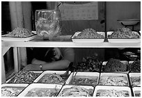 Vendor taking a nap at a food stall.. Chengdu, Sichuan, China (black and white)