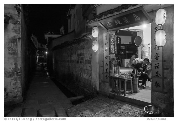 Shopkeeper and alley at night. Hongcun Village, Anhui, China (black and white)