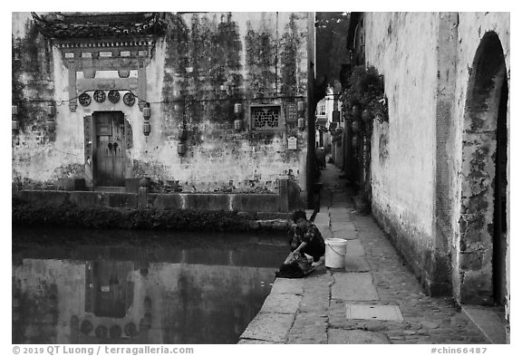 Woman washes laundry in Moon Pond. Hongcun Village, Anhui, China (black and white)