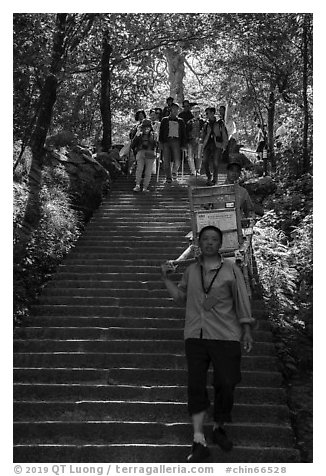 Sedan chair carriers on steep staircase. Huangshan Mountain, China (black and white)