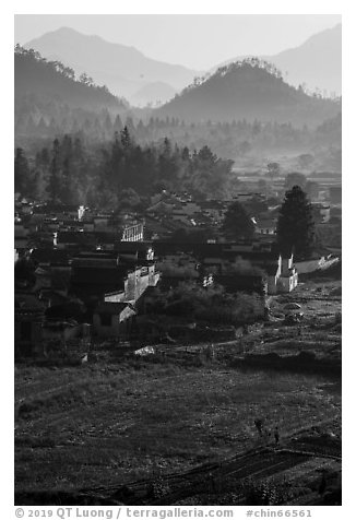 Villagers in fields and village in morning fog from above. Xidi Village, Anhui, China (black and white)