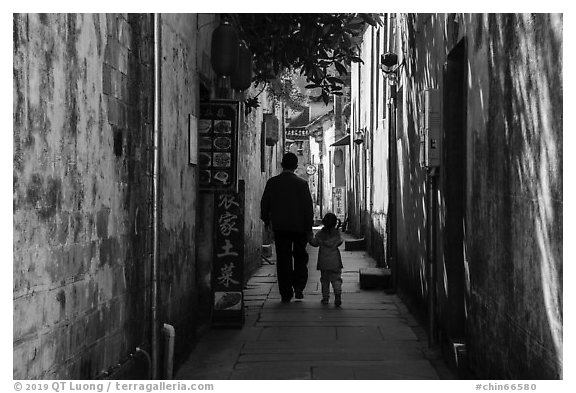 Father and daughter walking in alley. Xidi Village, Anhui, China (black and white)