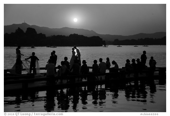Couple embracing at sunset among crowd, West Lake. Hangzhou, China (black and white)