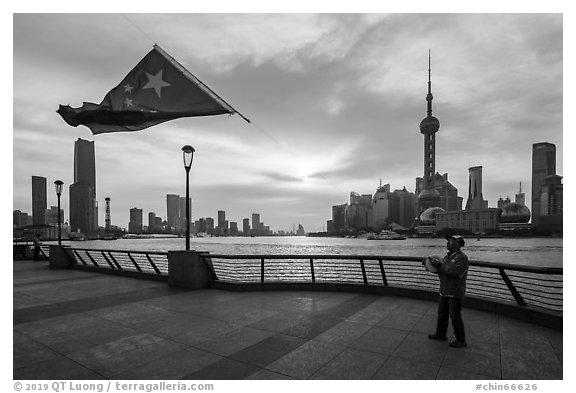 Man flying kite with Chinese flag attached on line, the Bund. Shanghai, China (black and white)