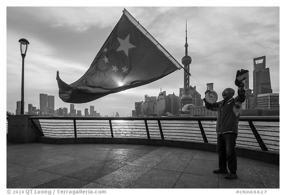 Man saluting Chinese flag and skyline, the Bund. Shanghai, China (black and white)