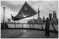 Man saluting Chinese flag and skyline, the Bund. Shanghai, China ( black and white)