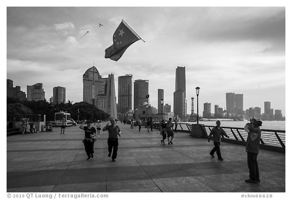 Joggers salute Chinese flag flown on kite line, the Bund. Shanghai, China (black and white)