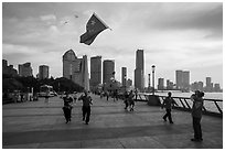 Joggers salute Chinese flag flown on kite line, the Bund. Shanghai, China ( black and white)
