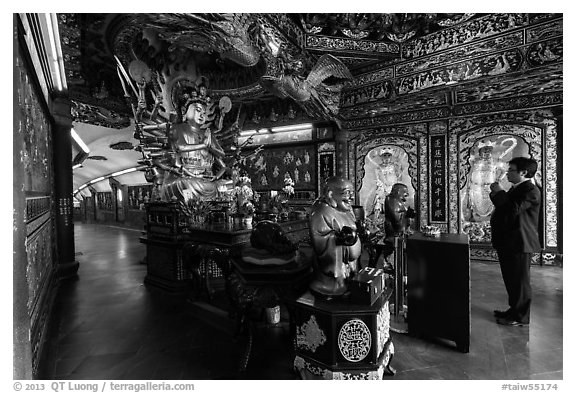 Tourist praying at tunnel entrance, Guandu Temple. Taipei, Taiwan (black and white)