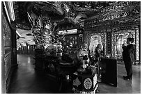 Tourist praying at tunnel entrance, Guandu Temple. Taipei, Taiwan (black and white)