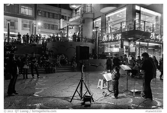 Tourists watch girl singing at night near the pier, Shueishe Village. Sun Moon Lake, Taiwan (black and white)