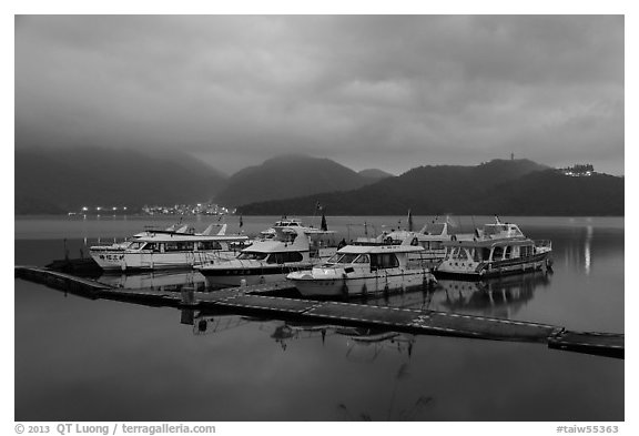 Pier with distant lights of Itashao Village and Syuanzang Temple at dawn. Sun Moon Lake, Taiwan (black and white)