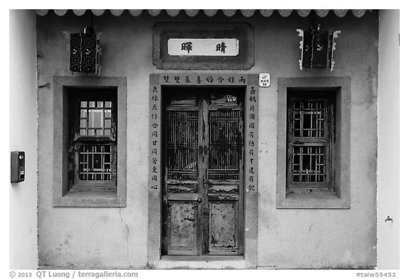 Facade of concrete building with wooden doors and windows. Lukang, Taiwan (black and white)