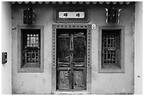 Facade of concrete building with wooden doors and windows. Lukang, Taiwan (black and white)