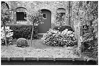 Small garden and brick house by the canal. Bruges, Belgium (black and white)