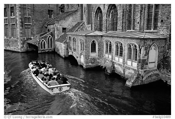 Tour boat goes by a church on a canal. Bruges, Belgium (black and white)