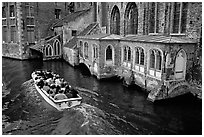 Tour boat goes by a church on a canal. Bruges, Belgium (black and white)