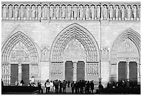 People standing in front of gates of Notre Dame Cathedral, late afternoon. Paris, France (black and white)
